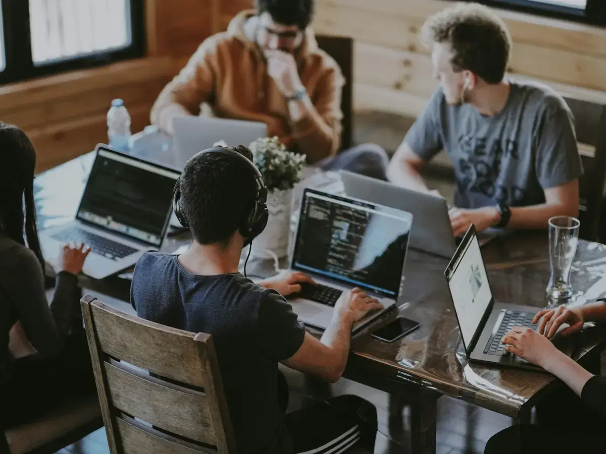 Developers collaborating on laptops around a table